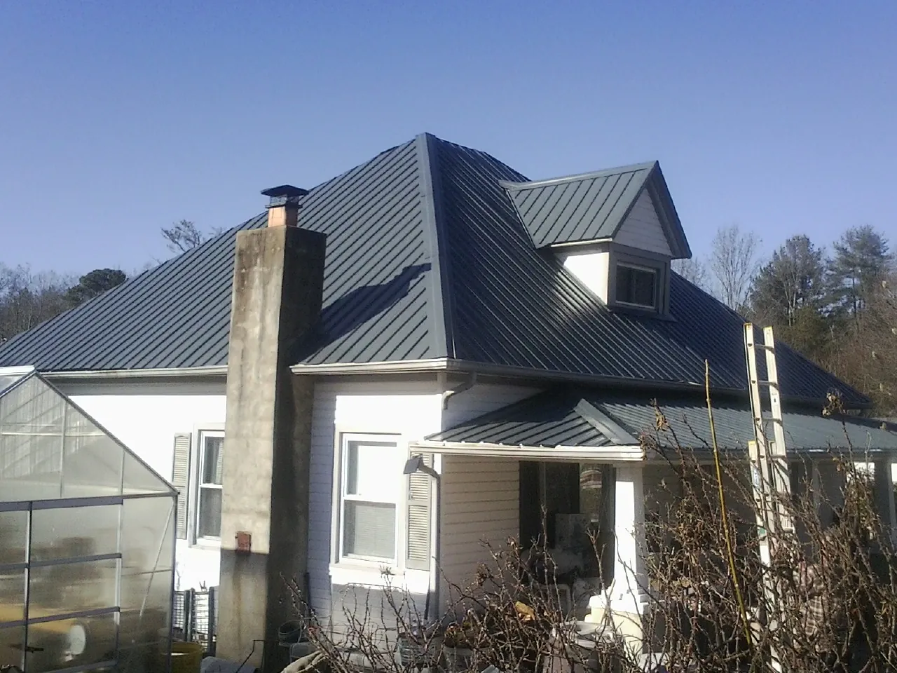 Dark blue standing seam metal roof on a white farmhouse with dormer — Slate & Tile Roof Repair by Roofing Brothers in Mulvane