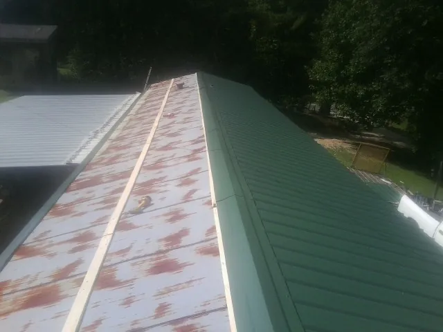 Old rusted panels beside newly installed green metal roofing — Wind Damage Roof Repair by Roofing Brothers in Mulvane