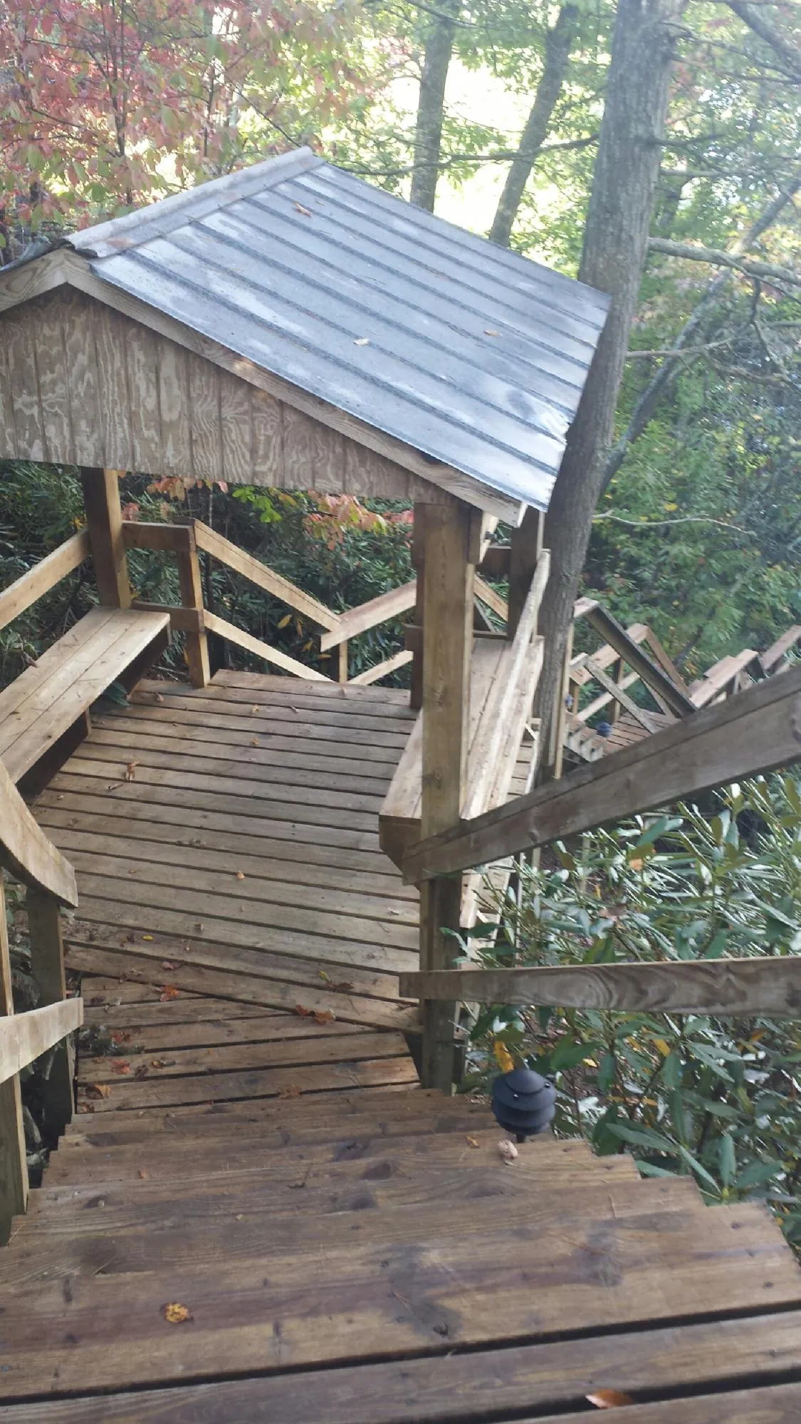 Metal roofed shelter over wooden steps on a wooded walkway — Skylight Repair & Installation work by our crew in Mulvane