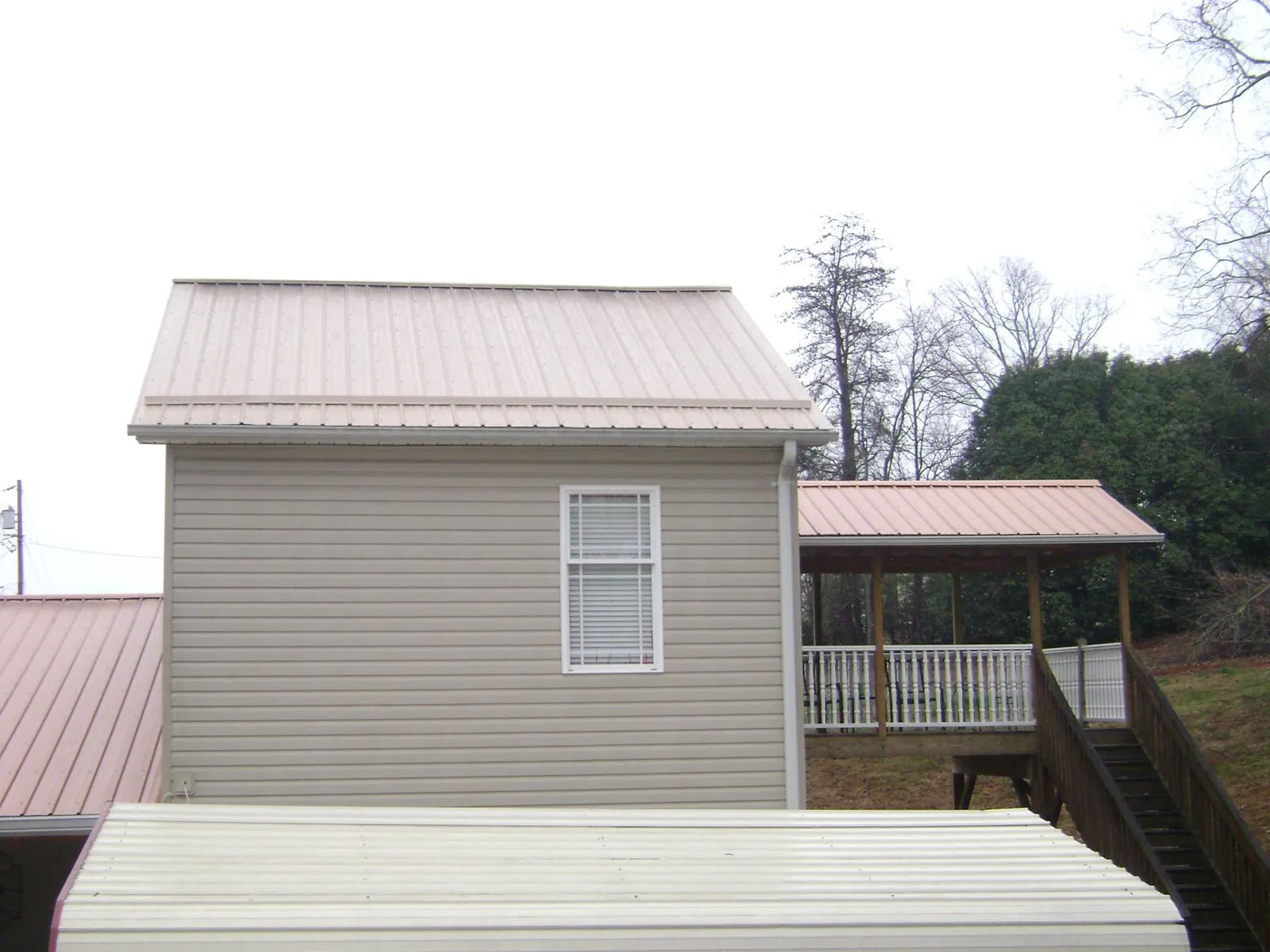 Tan metal roofs on a two story addition and attached porch, from a Roof Replacement job in Mulvane