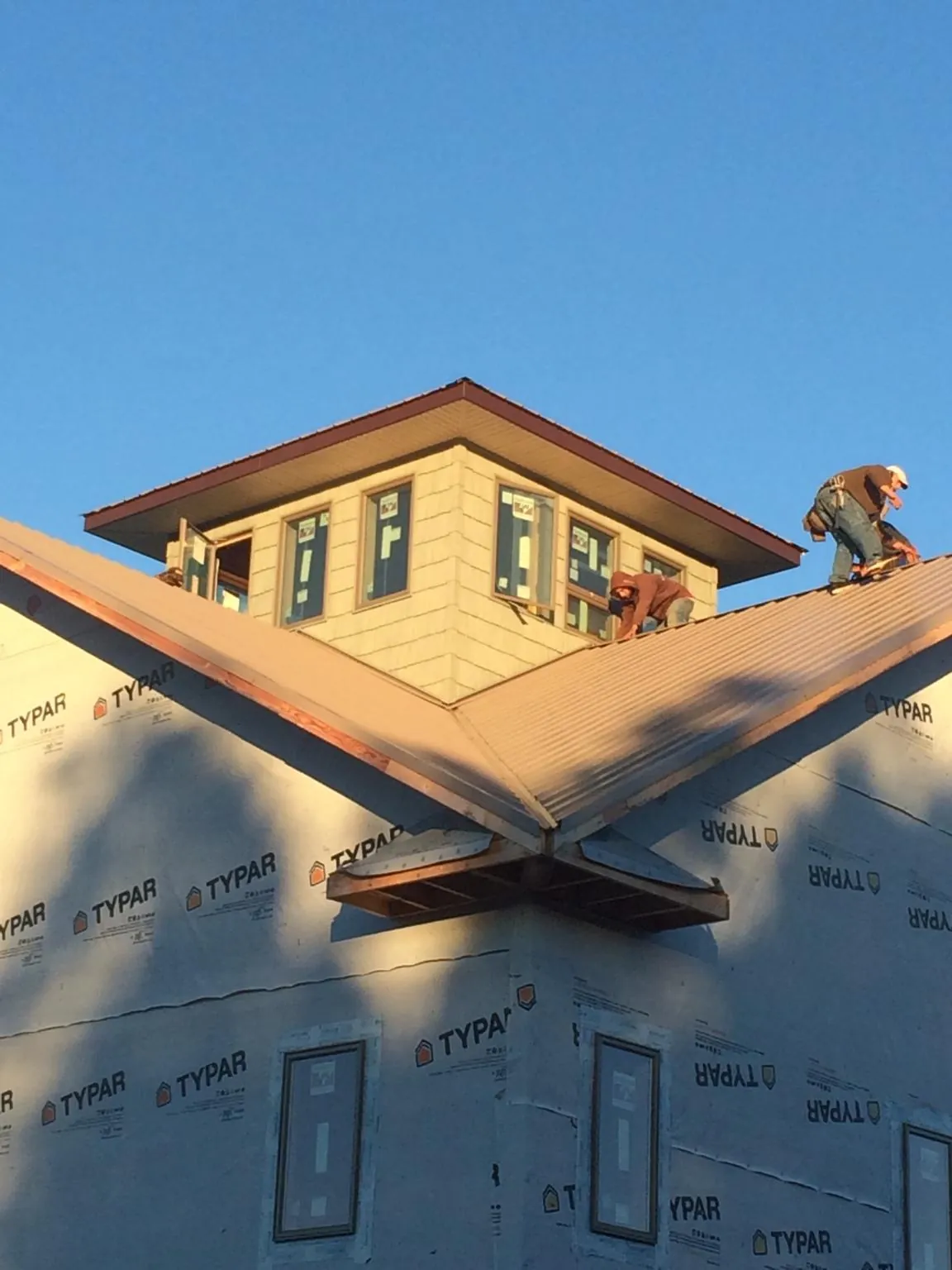 Roofers working around a rooftop cupola on a new metal roof at sunset — Roof Waterproofing in Mulvane by Roofing Brothers